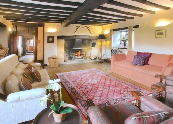 A large siting room with oak beams inglenook fireplace, sofas and armchairs.