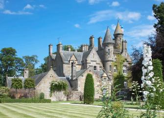 A multi-turreted Scottish castle in landscaped gardens.