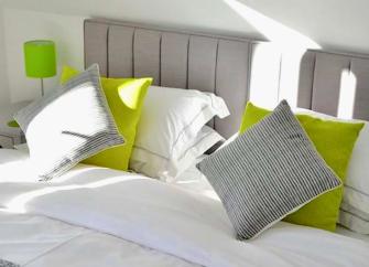 A double bed with pillows, scatter cushions, bedside tables an lamps.