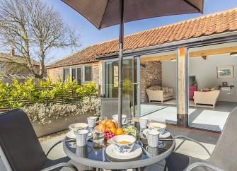 A single-storey barn conversion with folding French windows opening onto a dining terrace.