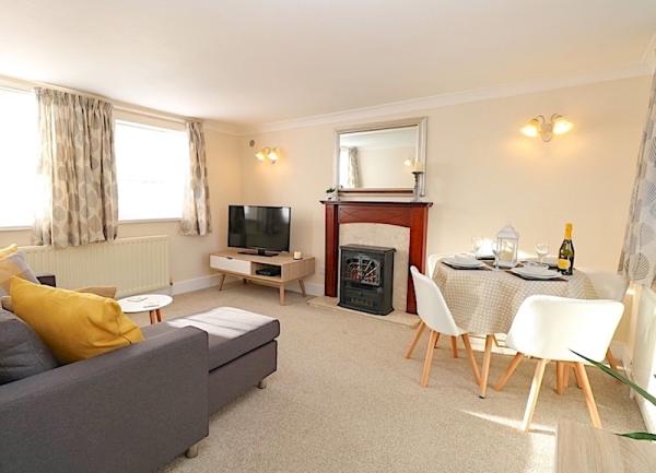 Living room with a sofa, TV and dining table for two.