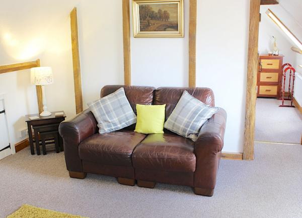Two-seat leather sofa in a lounge next to a side table with a table lamp.