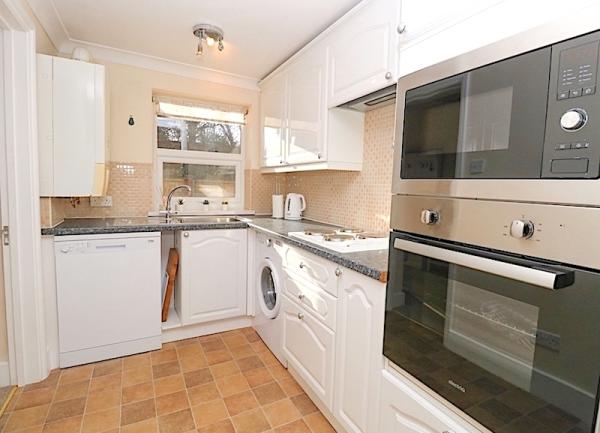 Fitted kitchen with mid-height oven, dishwasher and washing machine.