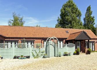 Exterior of a single-storey country cottage with a covered porch and fenced front garden.