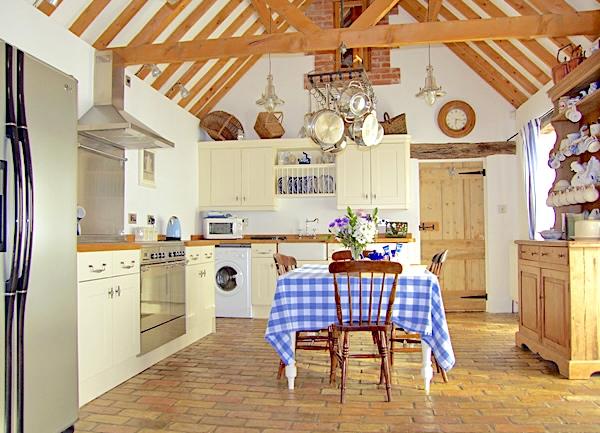 A fitted kitchen with American-syle fridge-freezer, cooker, washing machine. dining table and dresser.