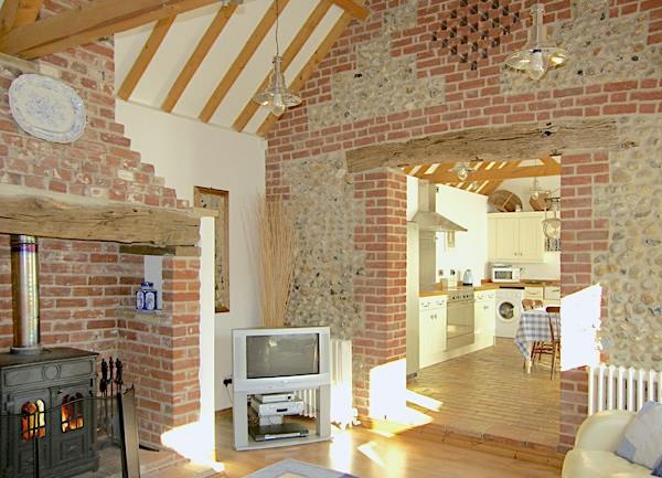 Lounge with an inglenook fireplace, TV and large arch doorway to the kitchen-diner.