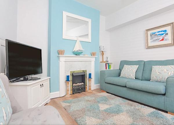 A lounge with sofa, armchairs open fireplace and widescreen TV.