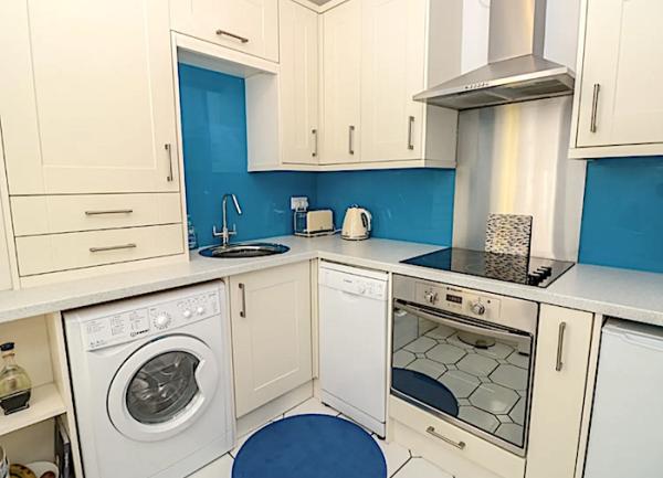 Cottage kitchen corner with oven, washing machine and dishwasher.
