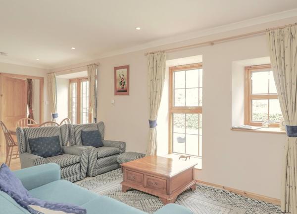 Lounge with sofas, coffee table and French window with a dining area to the rear.