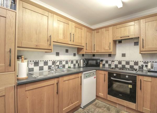 A fitted kitchen with floor and wall-mounted cupboards with integrated  gas cooker and dishwasher.