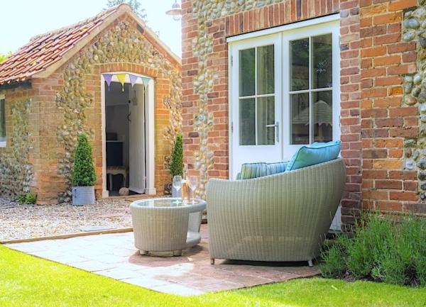 An armchair and glass-top table on a patio outside a set of French Windows.