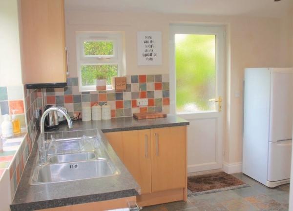 3. Exmoor cottage kitchen with sink, fridge-freezer and door to garden.