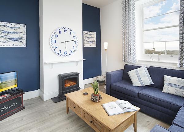 A cosy lounge with a woodburner, sofas, coffee tables and TV.