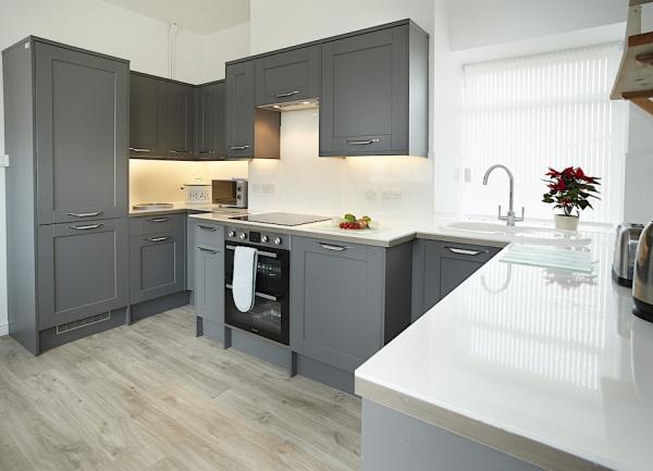 A smart fitted kitchen with floor and wall-mounted cupboards with oven and dishwasher.