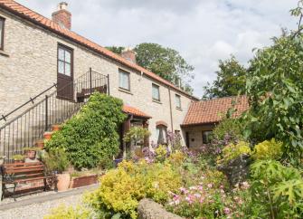 Exterior of a large barn conversion with external steps to 1st flor front door - facing a mature garden