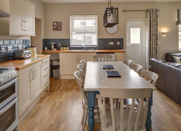 Fitted kitchen with wrap-around units with built-in appliances and dining table.
