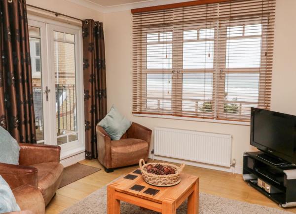 Lounge with leather armchairs, coffee table, TV and front-row beach views.
