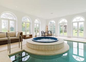 A jacuzzi sits within a large indoor swimming pool.