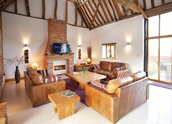 A lounge with an oak-beamed arch ceiling, leather 3-piece suite and a woodburner. 
