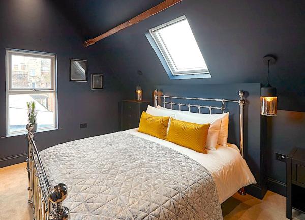 Dual aspect double bedroom with contemporary brass bed and twin, wall-mounted bedside lights.