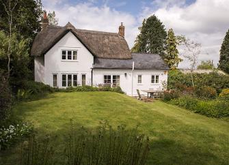 A partially thatched Dorset cottage overlooks a large and secure lawned garden.