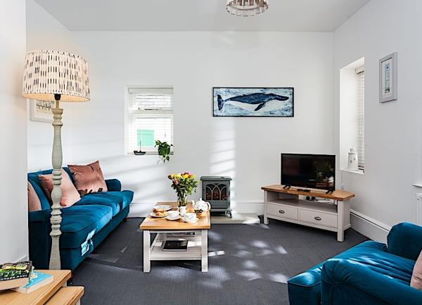 Lighthouse cottage lounge in Padstow with sofas, coffee table, TV and electric flame-effect wood-burner.