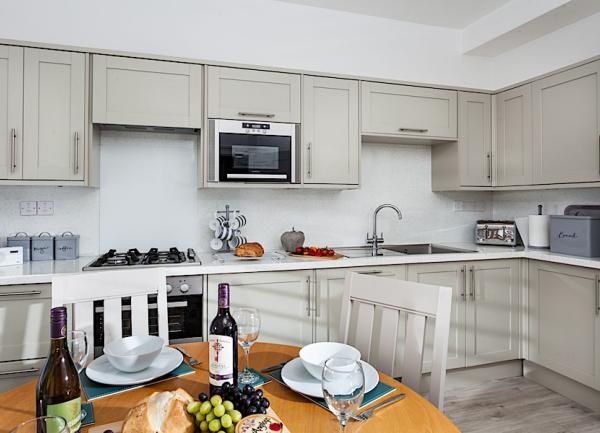 Padstow cottage kitchen-diner with gas hob, microwave, toaster and dining table laid for breakfast.