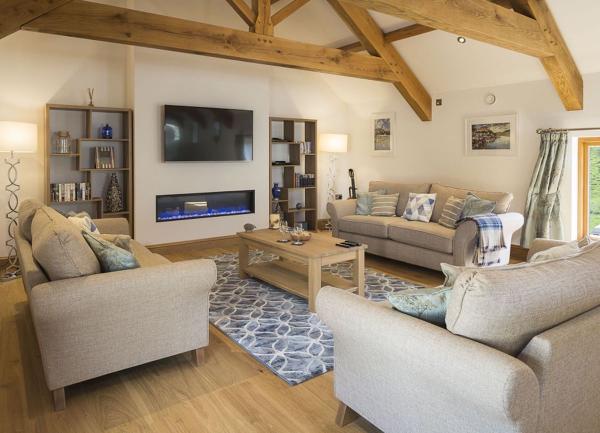 A large lounge with oak-beam trusses, widescreen TV, 3 sofas and a coffee table.