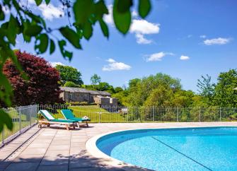 Outdoor swimming pool with table of drinks and snacks in front.
