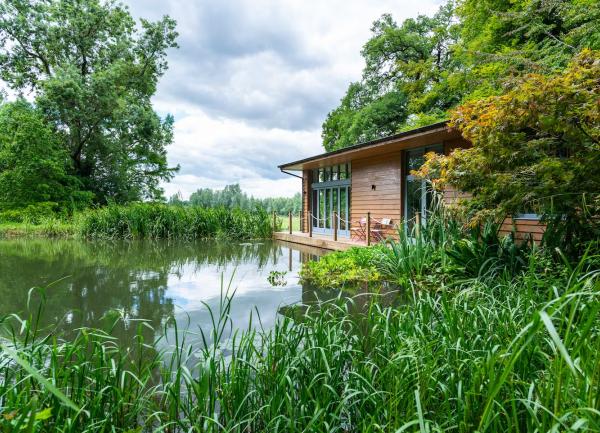 A holiday home sits on the edge of a lake surrounded by trees.