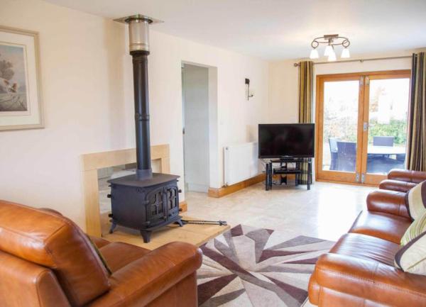 Lounge with brown leather sofas, TV and a wood burner