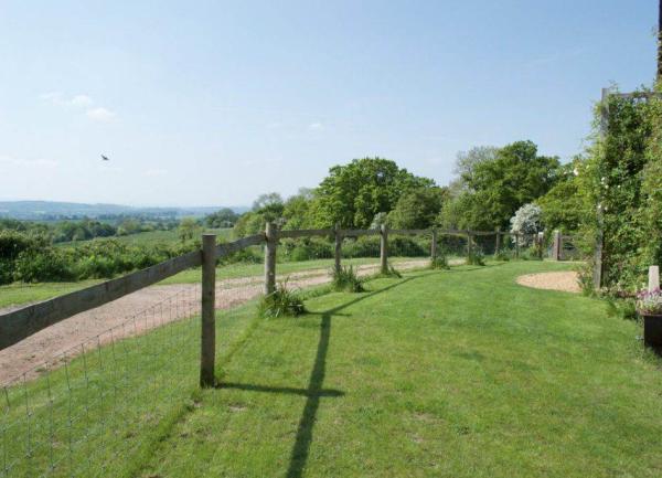 A fenced lawned garden with hills and trees in the distance