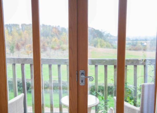 Patio doors looking onto a balcony with seating and views green hills and trees