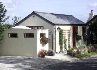Single-storey exterior of a white-rendered bungalow with hanging flower baskets.