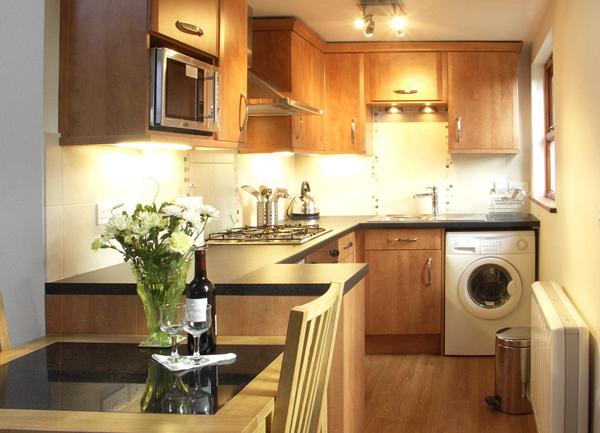 A fitted kitchen with a washing machine and a dining area in the foreground.