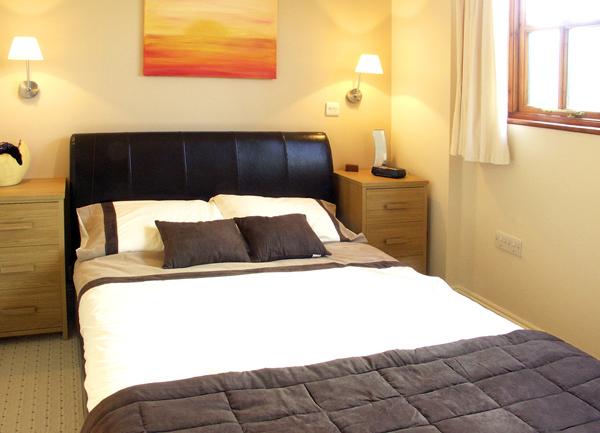 A double bedroom with bed and twin bedside cabinets with table lamps.