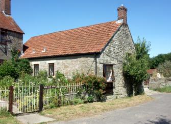 A stone-built somesret holiday cottage with a mature garden overlooks a quiet lane.