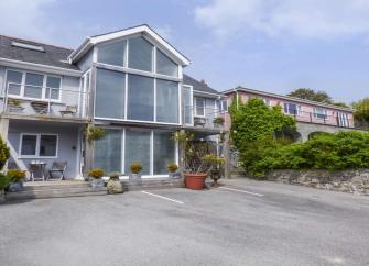 A large, contemporary 3-storey apartment building with a central gable of floor-to-ceiling windows.