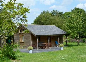 A single storey wooden barn conversion with an extended roof to create a sheltered terrace.
