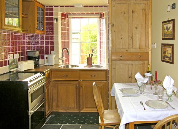 A kitchen diner with an oven with ceramic hob and dining table laid for dinner. for two.