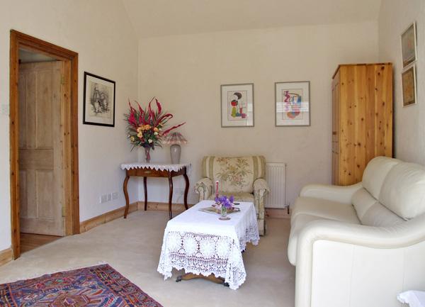 A lounge with a leather armchair, coffee and side tables, an armchair and pine cupboard.