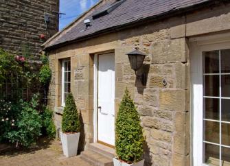 Exterior  of a stone-built, single-storey Chirnside holiday cottage.