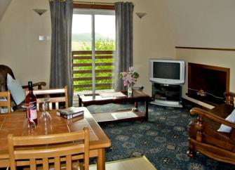 A comfortably furnished,  carpeted lounge with French windows offering rural views.
