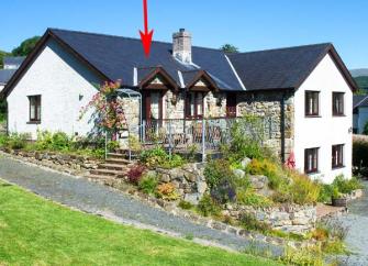 A large L-shaped Gwynedd holiday cottage house with a deck and rockery garden. garden.