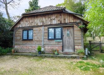 Exterior of a wooden eco-lodge near Ringwood backed by mature trees.