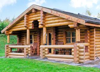 Front of a log cabin showing a covered deck.