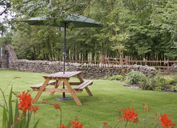 Picnic table with parasol on a lawn.