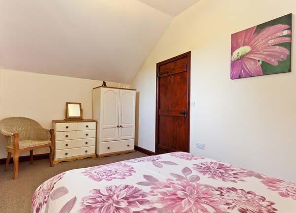 Double bed with wardrobe, chest-of-drawers and armchair.