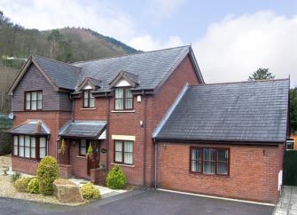 Exterior of modern a 2-storey brick house facing a garden with off-road parking for 2-3 cars.