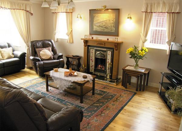 Lounge with pollished pine-floorboards,sofas, armchair, coffee table and open fireplace.